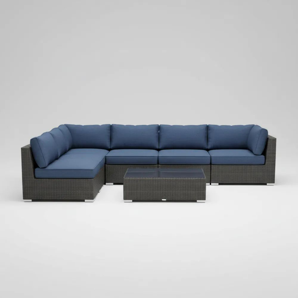 Juego de sofás de ratán gris con cojines azules y mesa de vidrio templado