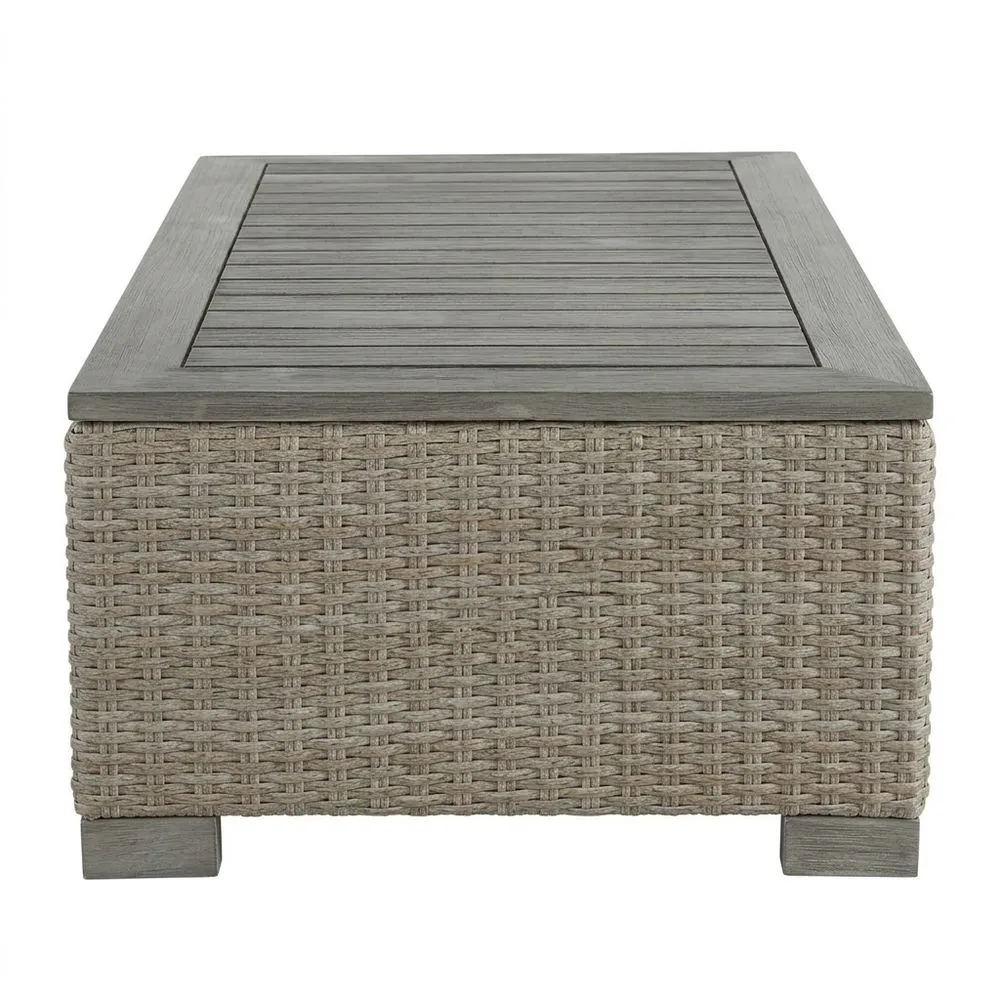 Una mesa de centro hecha de madera de acacia y ratán artificial, en color gris.