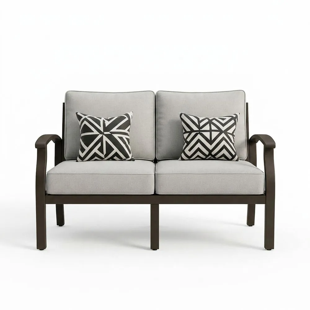 Un sofá de jardín de aluminio de dos plazas con cojines grises.