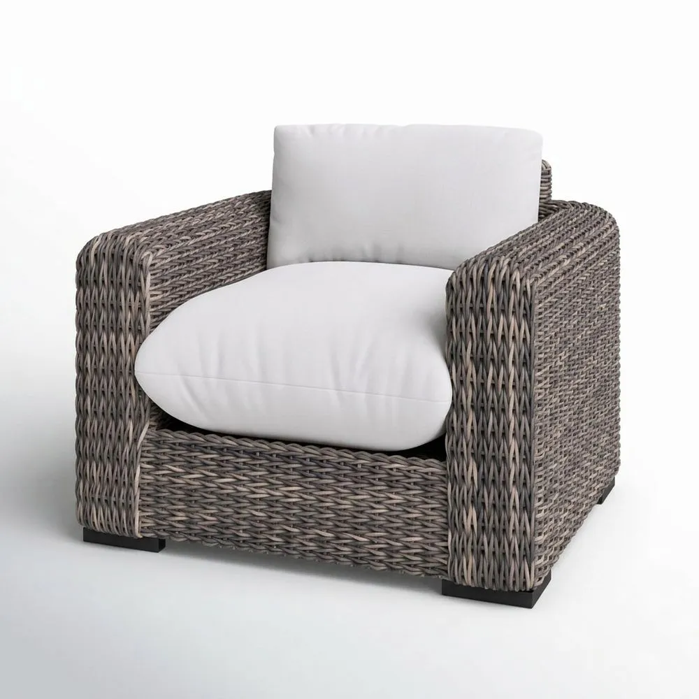 Sillón gris de ratán sintético con cojines de asiento blancos.