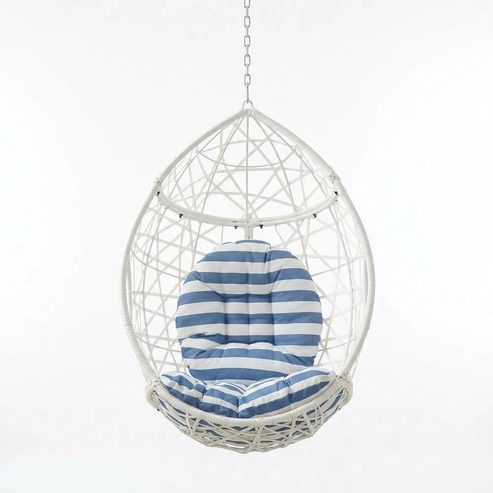 Silla colgante de ratán sintético blanco con cojines a rayas azules y blancas.