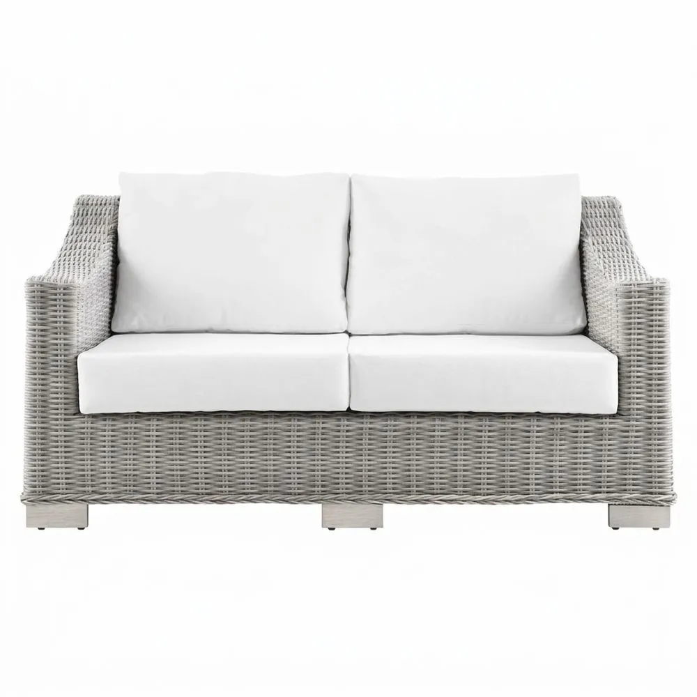 Sofá de dos plazas de ratán sintético gris con cojines blancos