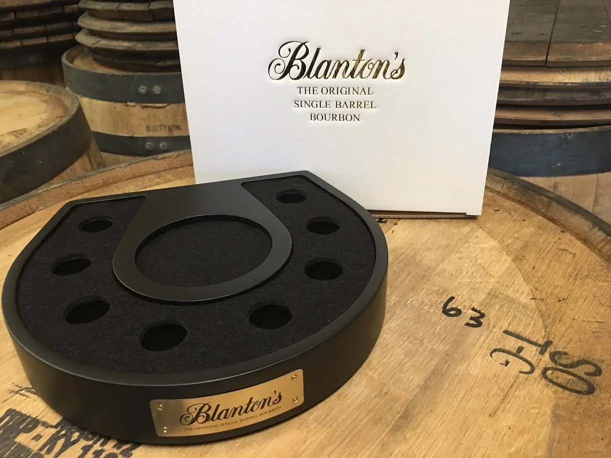 Empty horseshoe-shaped display stand with eight stopper positions and center bottle opening