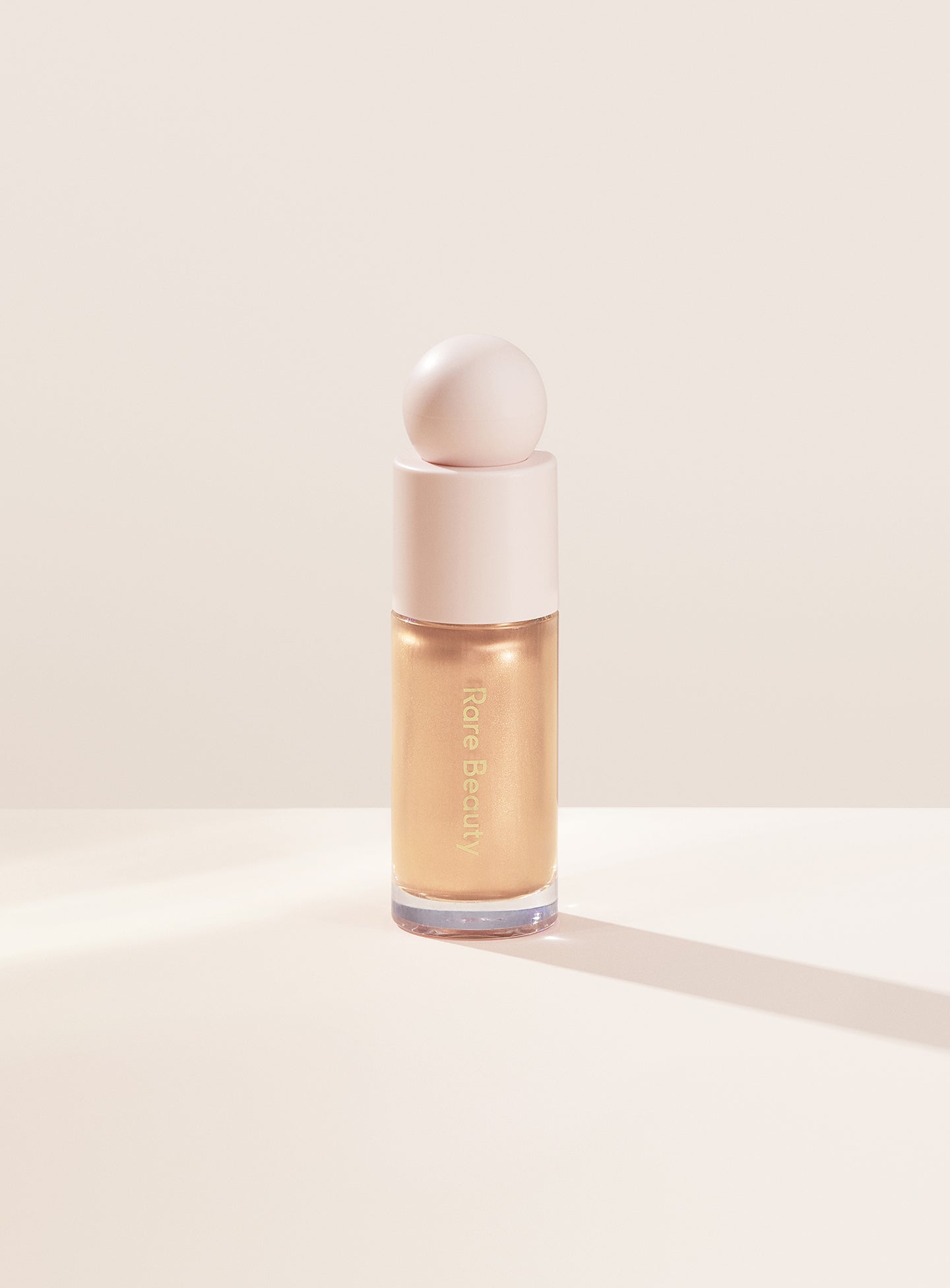 Exhilarate| Rare Beauty's Positive Light Liquid Luminizer in the champagne gold shade "Exhilerate."