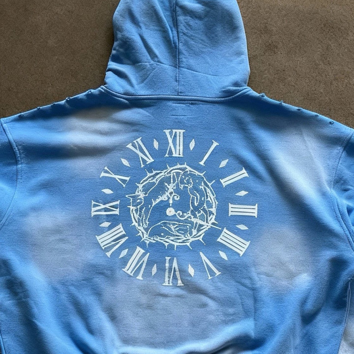 Blue hoodie with a white graphic design on the back against a brown background