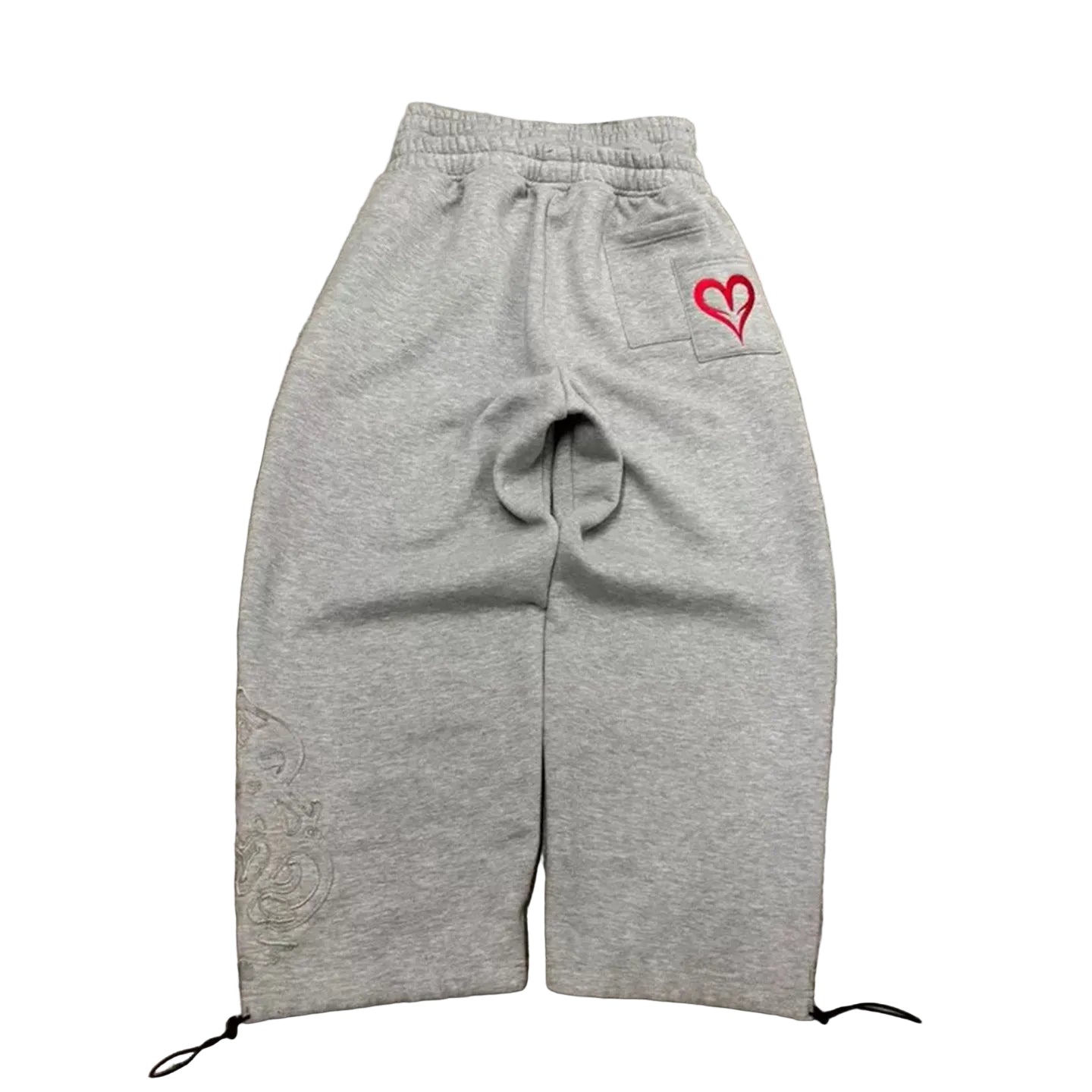 Gray sweatpants with a red heart logo on a concrete surface