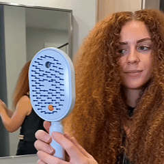 Replace with a square lifestyle image of a woman with smooth groomed hair holding the rechargeable spray massage comb