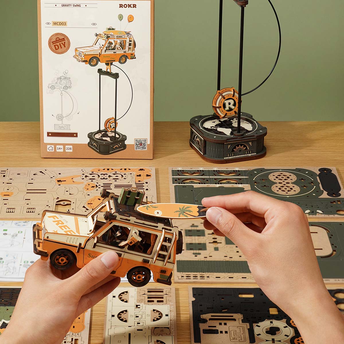 Scène d'assemblage ROKR Road Tripper MCD03 avec boîte de produit et feuille de pièces en bois