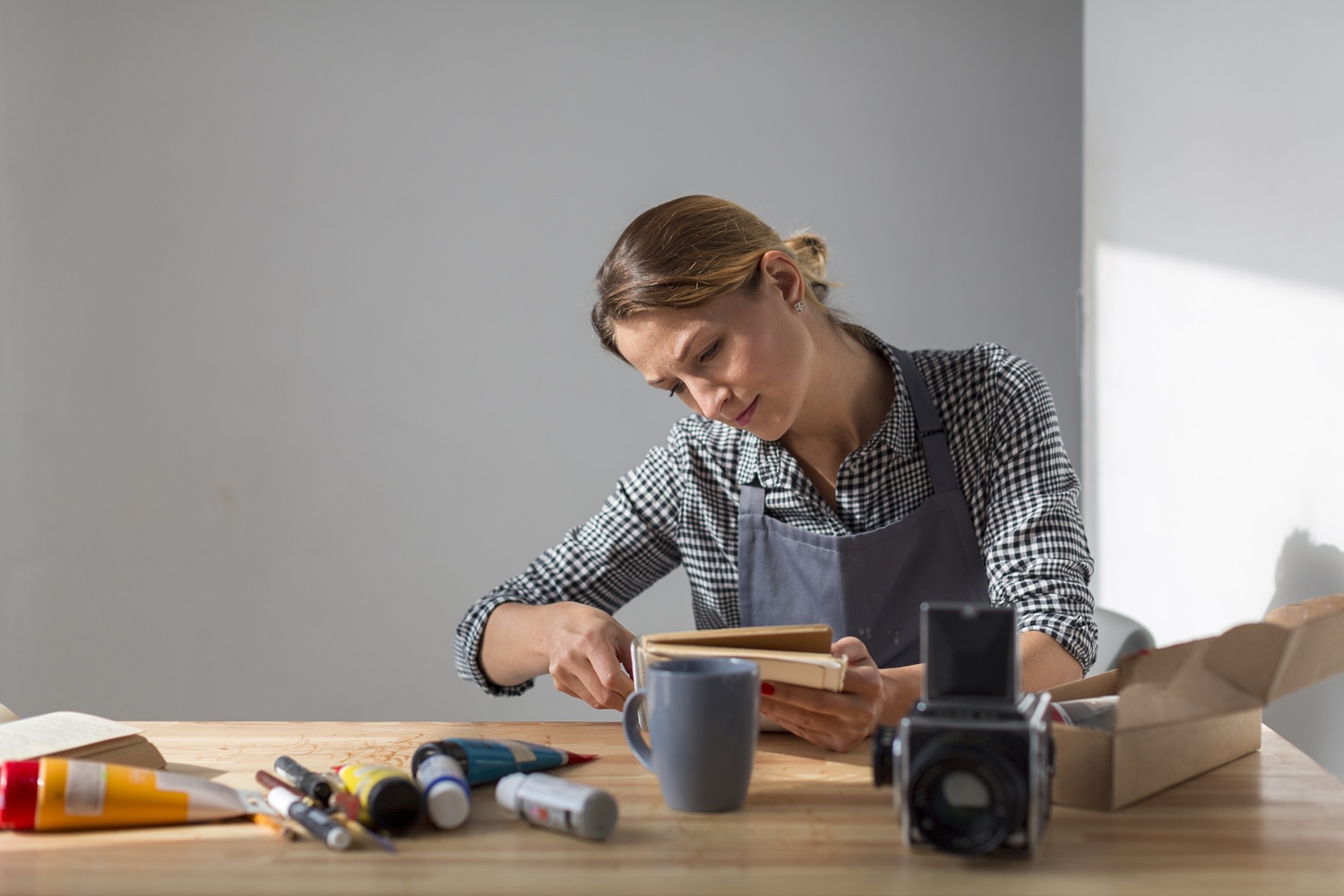 Vue de face d’une femme à son bureau tenant un livre