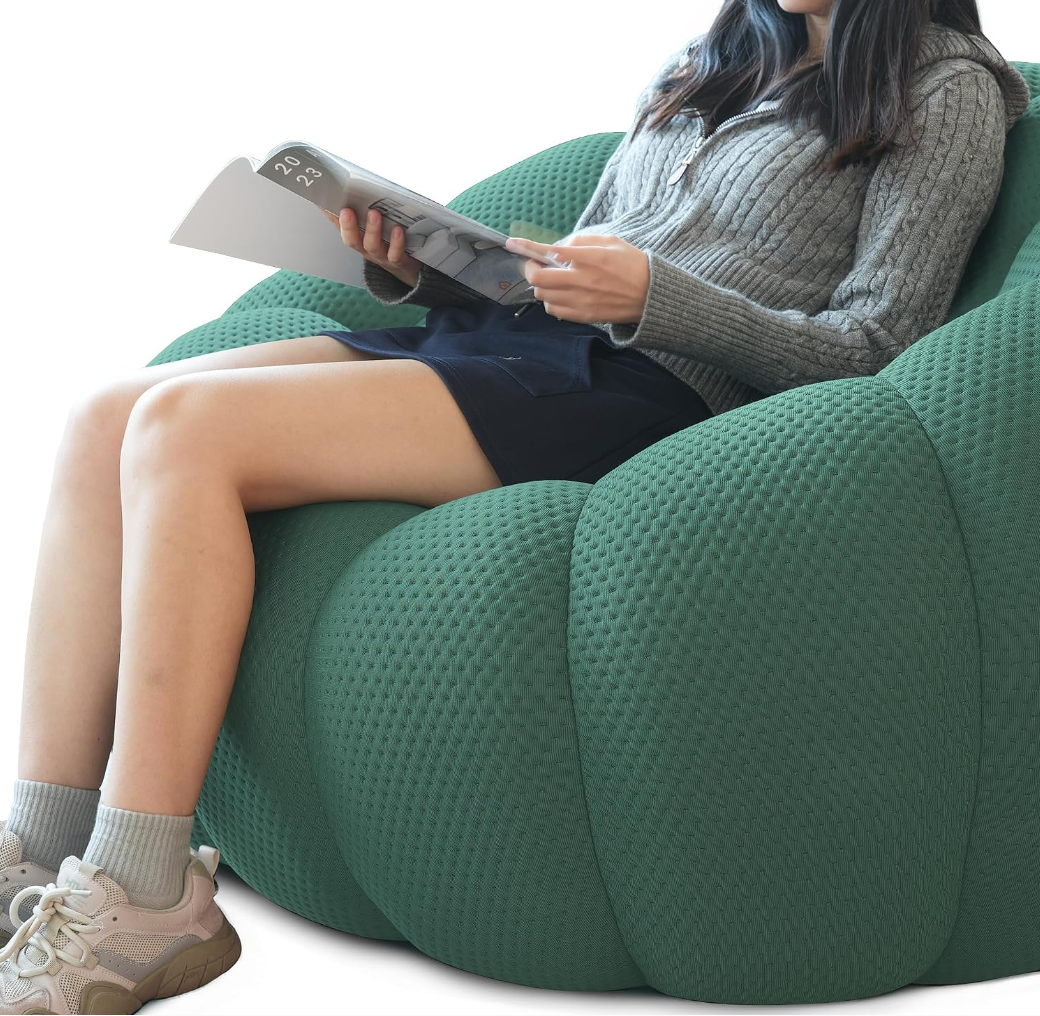 Person reading a book comfortably in a wide-seated bubble sofa, cozy indoor reading nook with soft plush cushion