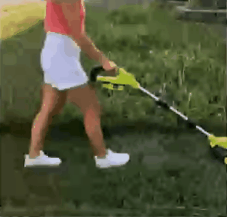 Woman using cordless grass cutter on lawn