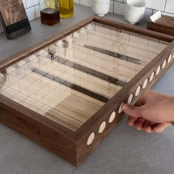 Hand pressing push-to-open drawer on walnut chopstick display box with clear top