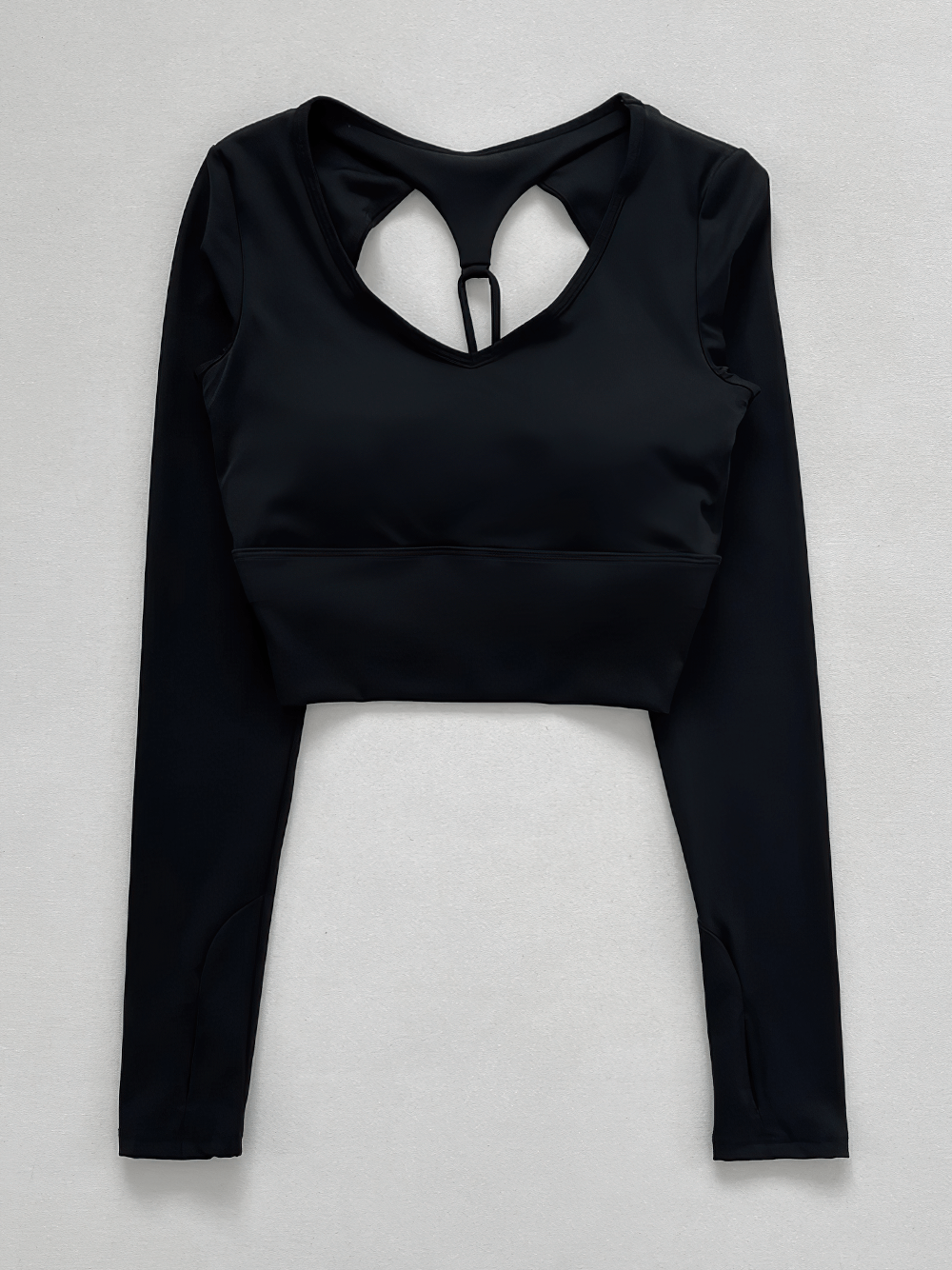 Woman wearing a sexy hollow-out shoulder straps sports top with long sleeves, ideal for yoga and workouts.