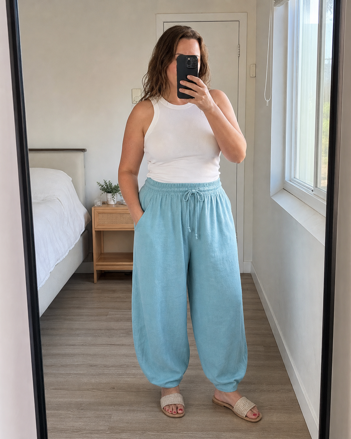 Midsize model wearing aqua-blue linen-blend wide-leg palazzo pants in a bedroom mirror scene