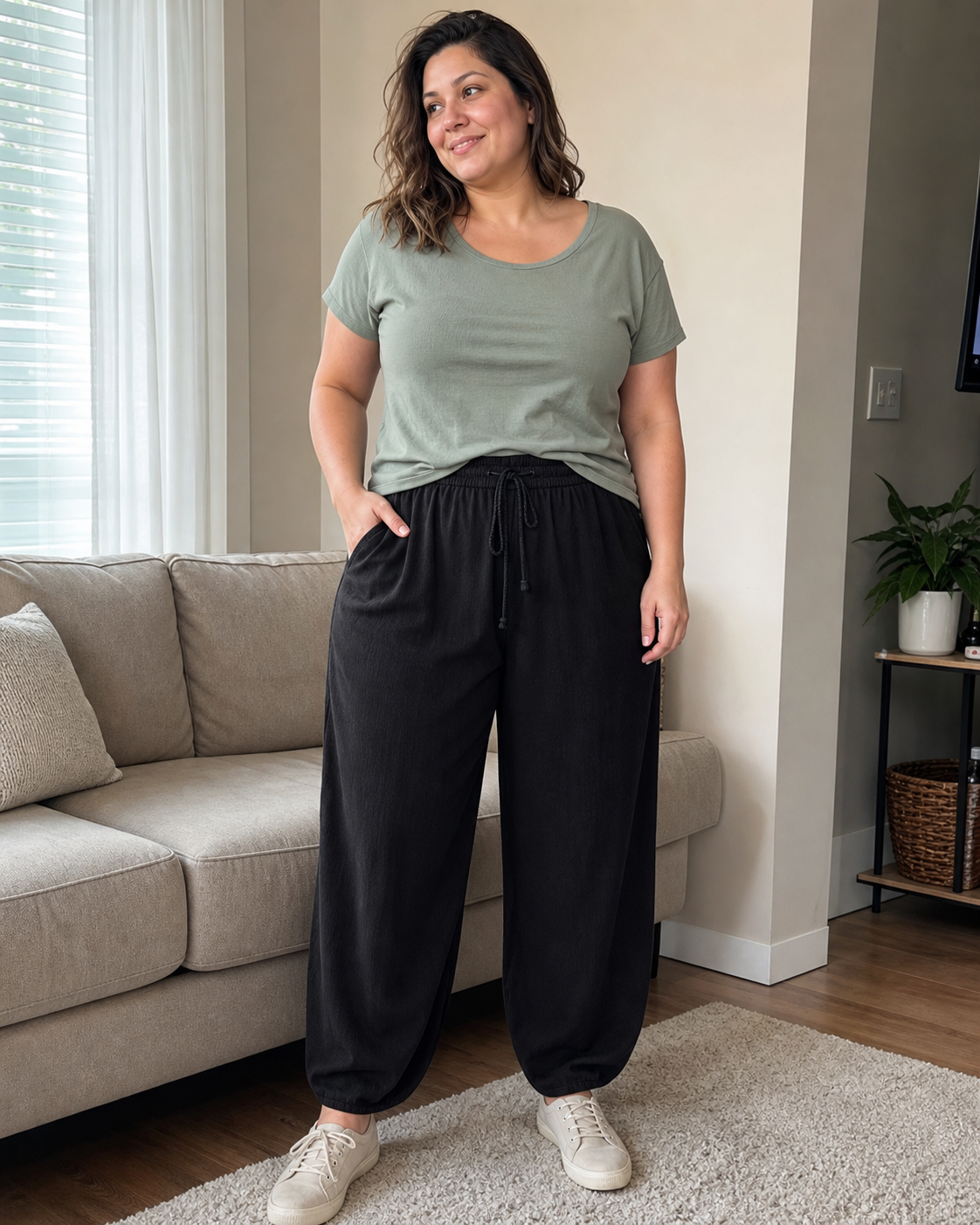 Curvy model wearing black linen-blend wide-leg palazzo pants in a lived-in living room beside a sofa