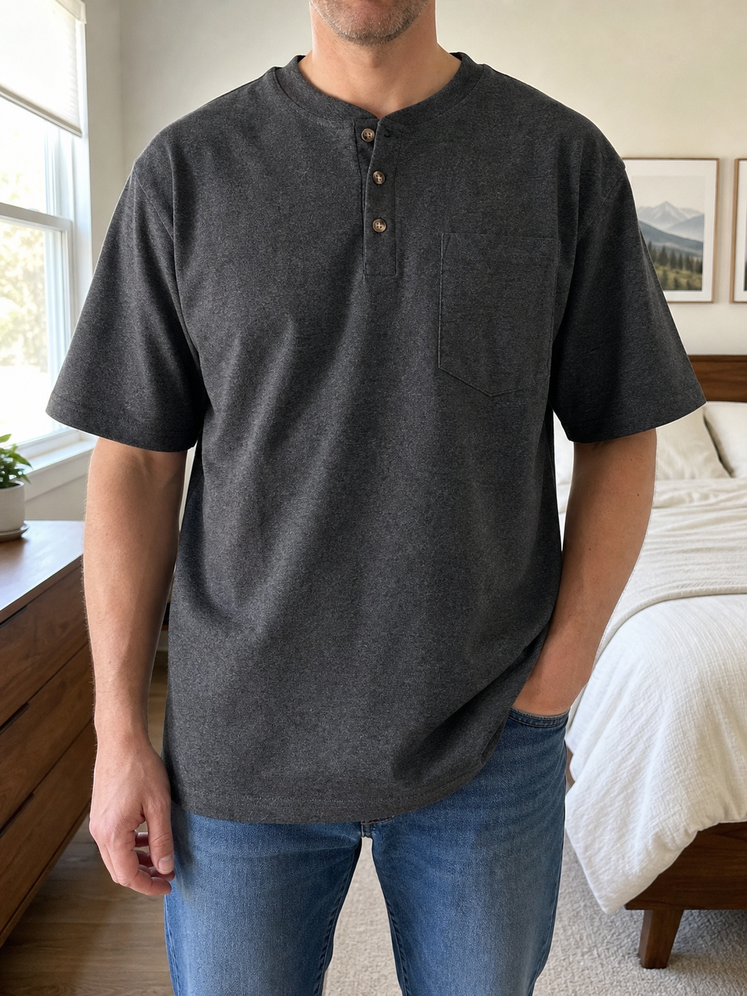 Midsize model wearing the carbon heather three-button pocket Henley in a bright bedroom
