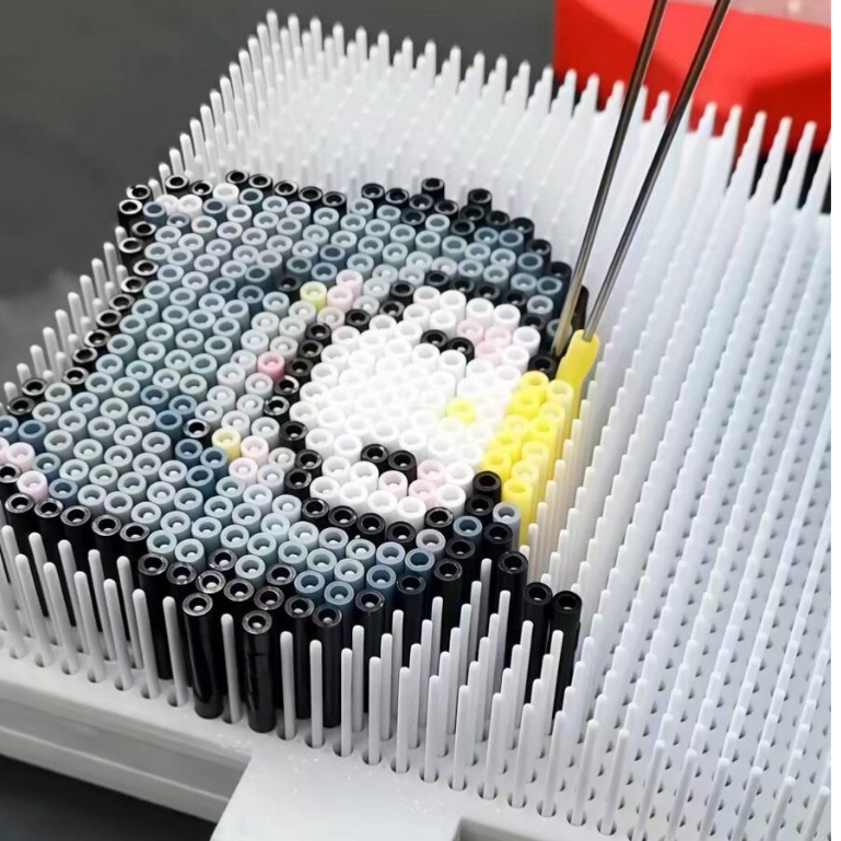 Close-up of a raised fuse bead pegboard with colorful beads being placed with a tool