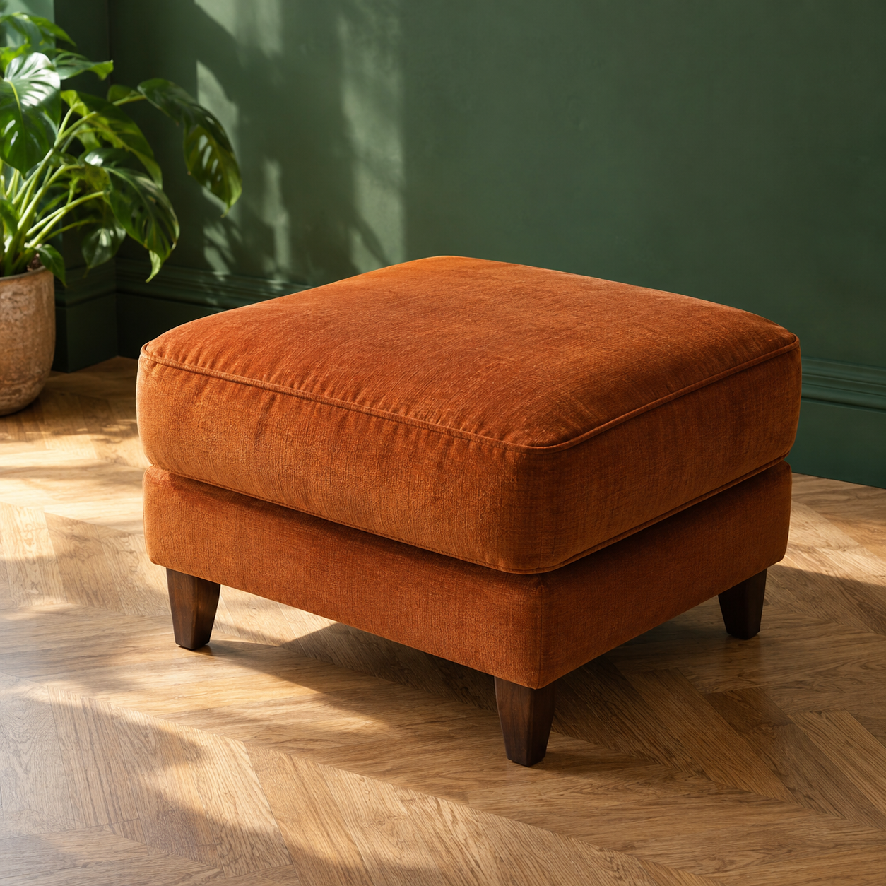 Terracotta upholstered stool against a deep green wall