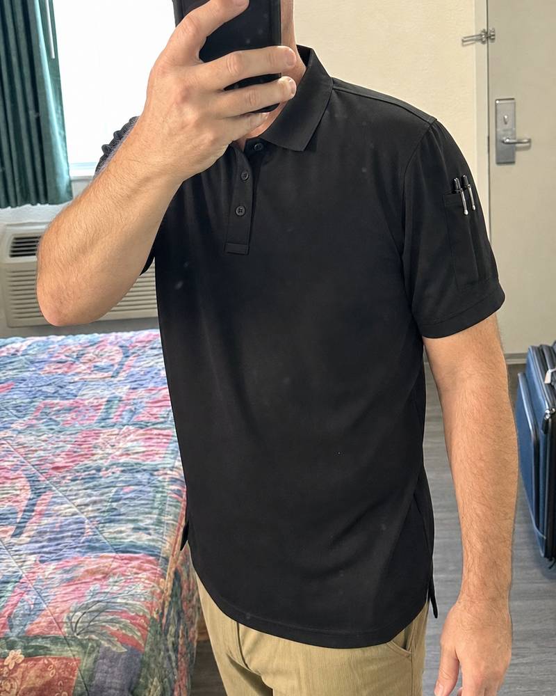 Black tactical performance polo shown in a casual motel mirror selfie