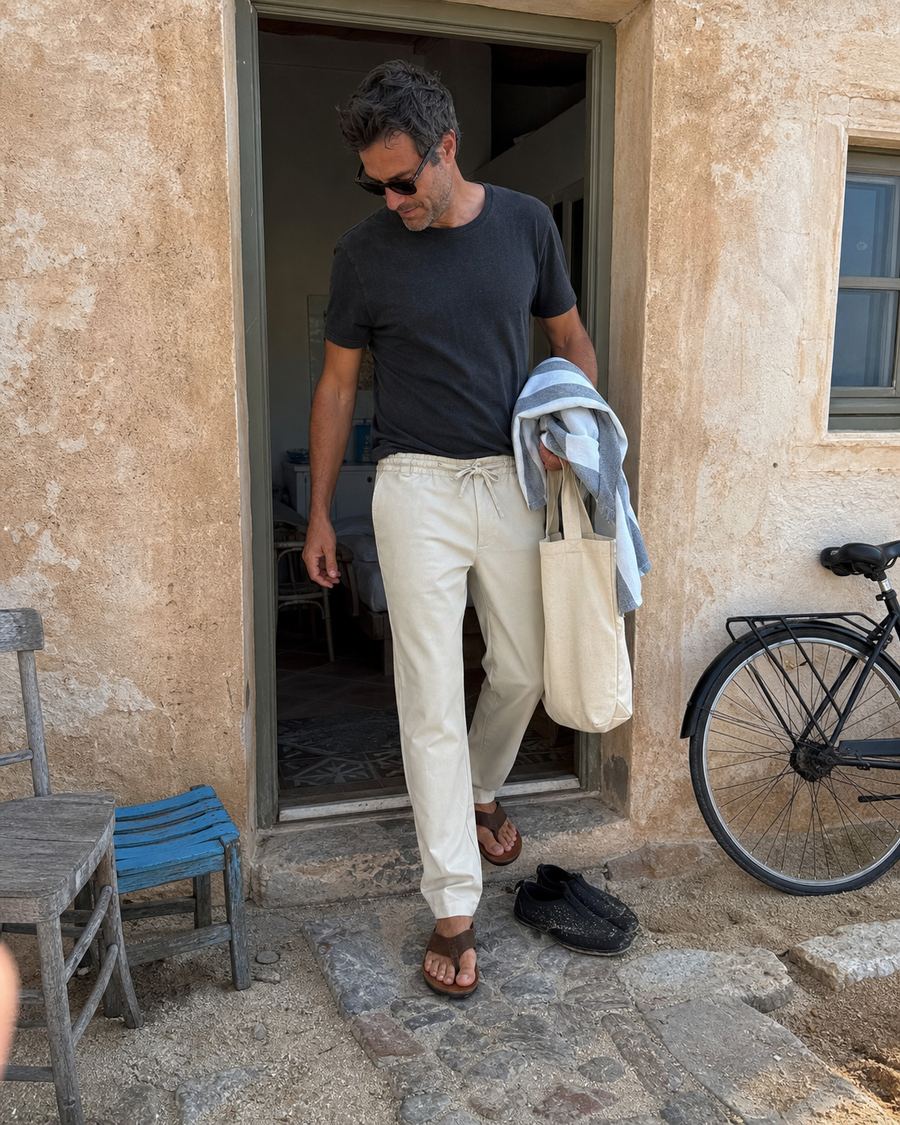 Light beige drawstring linen pants worn outside a coastal guesthouse