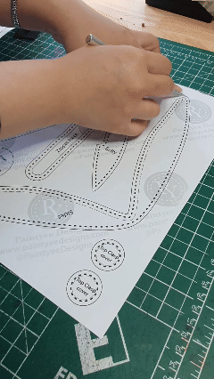 Maker tracing and preparing the bat purse pattern before cutting leather