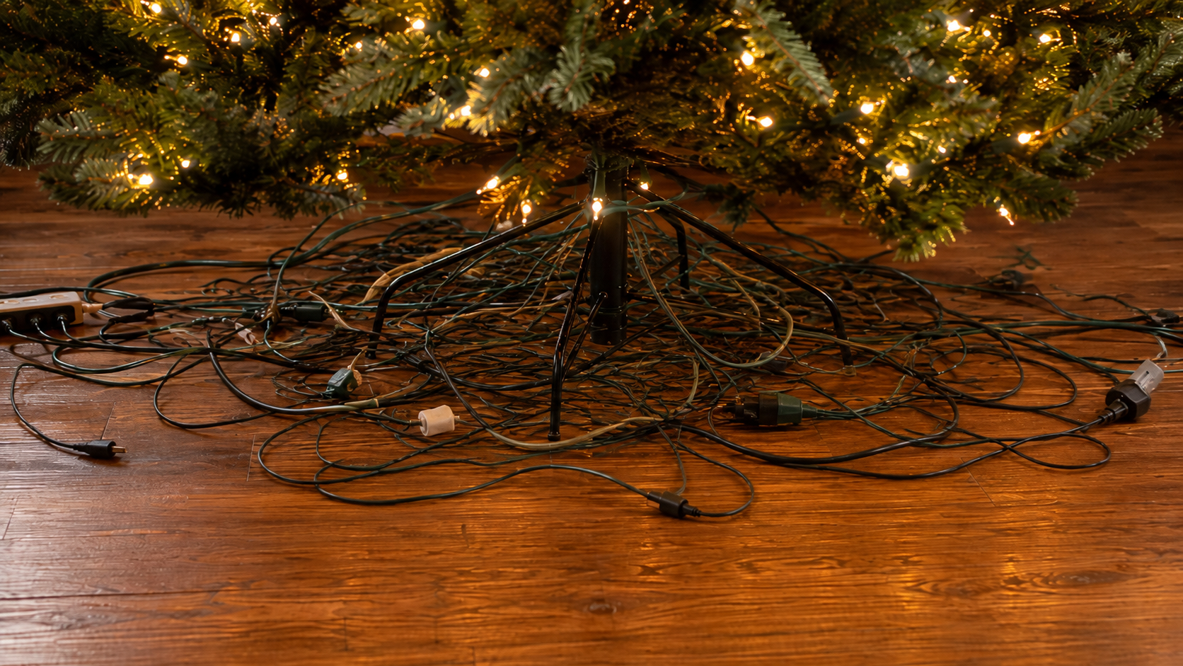 Suggested image: Christmas tree with visible metal stand and cords before adding a tree skirt