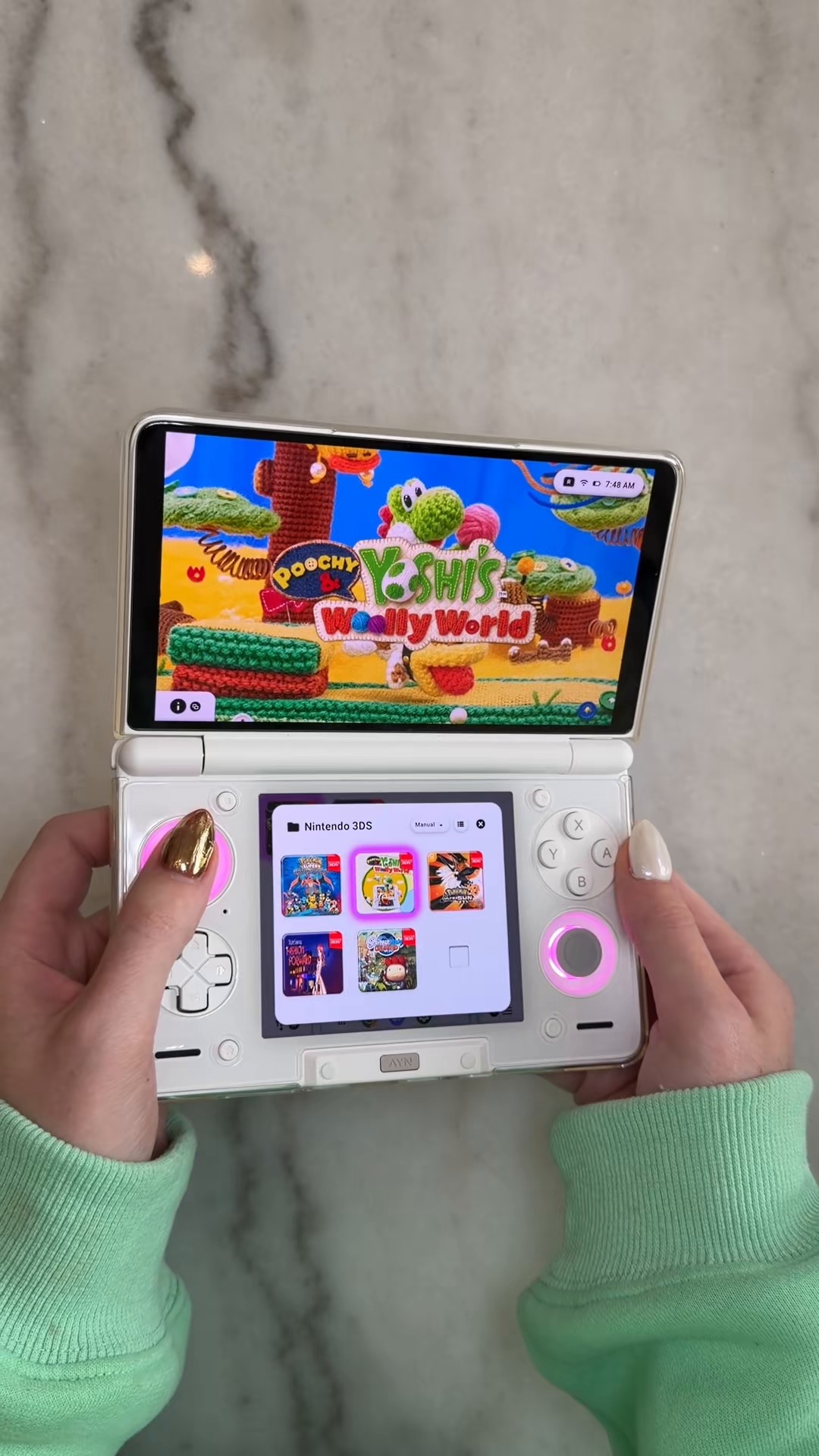 White dual-screen Android gaming handheld in use