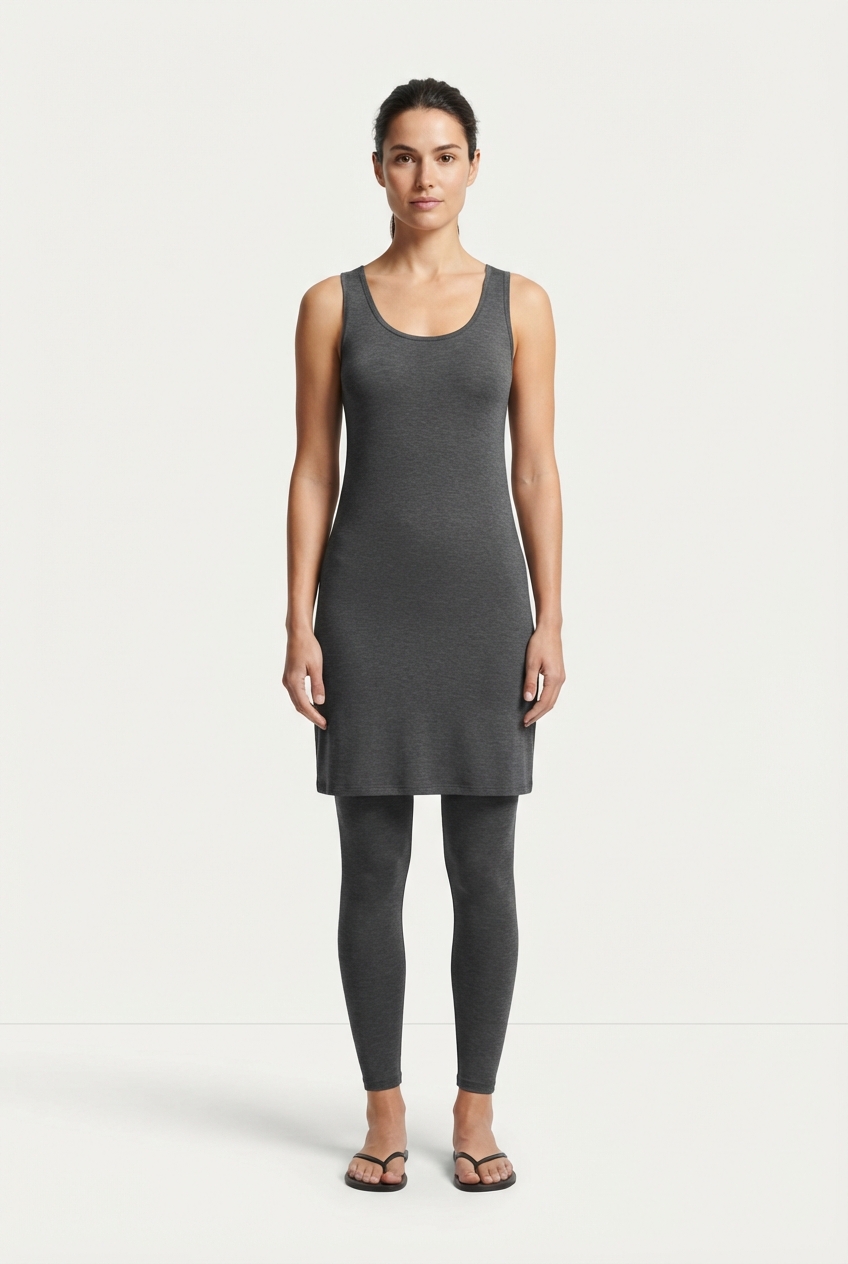 Model wearing a darkgray minimalist tank dress against an off-white studio background