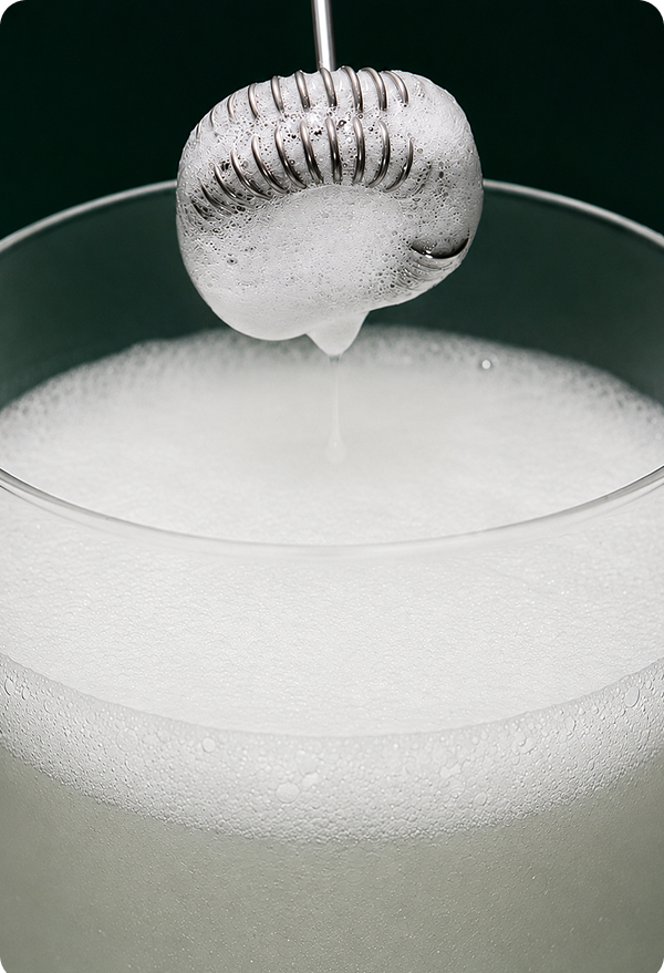 A whisk lifting foam from a glass of freshly stirred Super Fiber