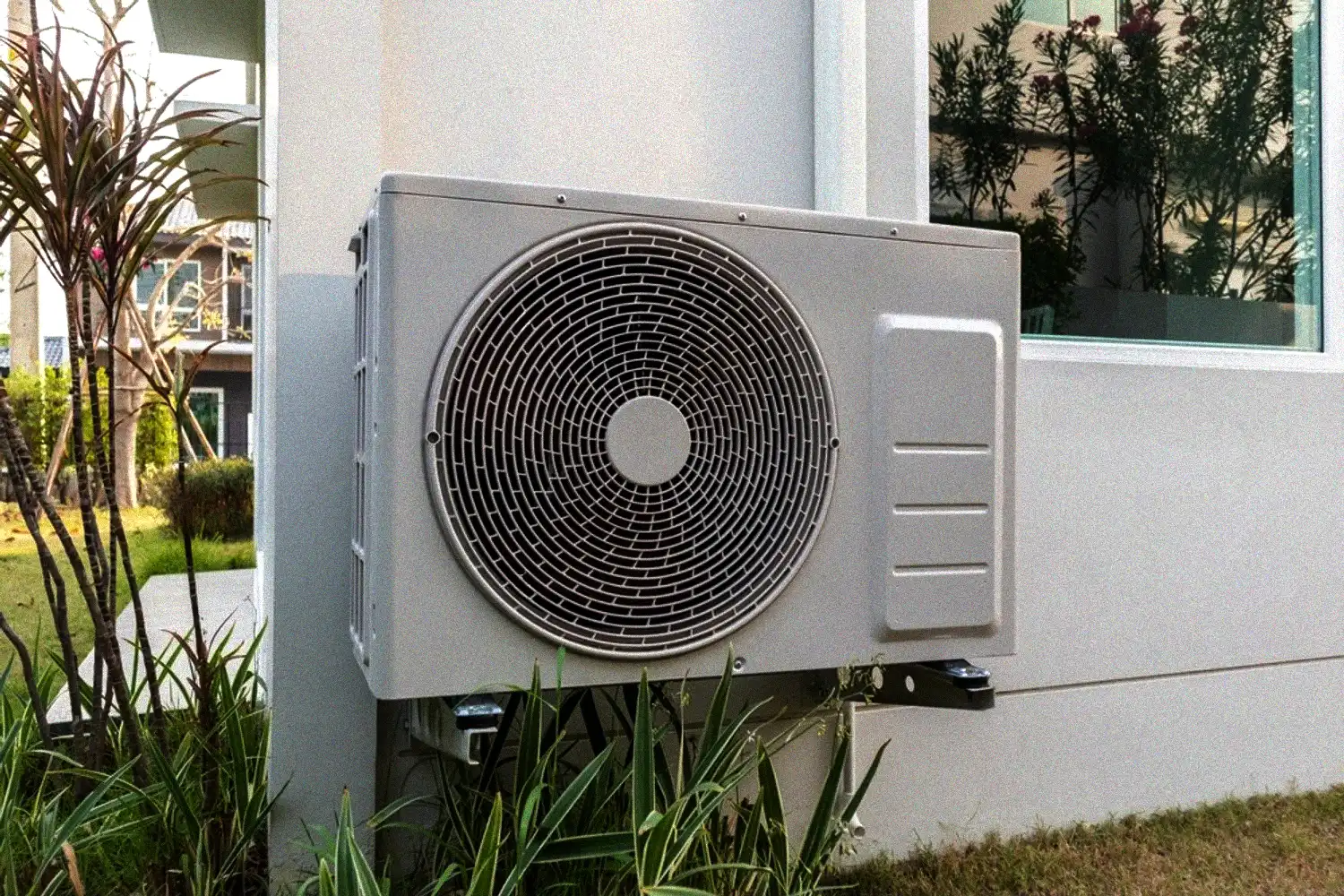 Outdoor residential AC condenser unit installed beside a home for refrigerant-based cooling.