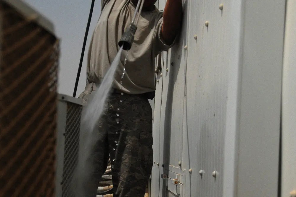 HVAC technician removing sand and buildup from an air-conditioning coil