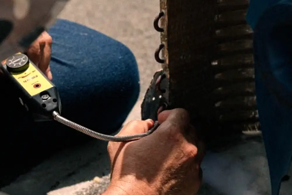 Technician inspecting internal components of an air-conditioning unit during professional maintenance