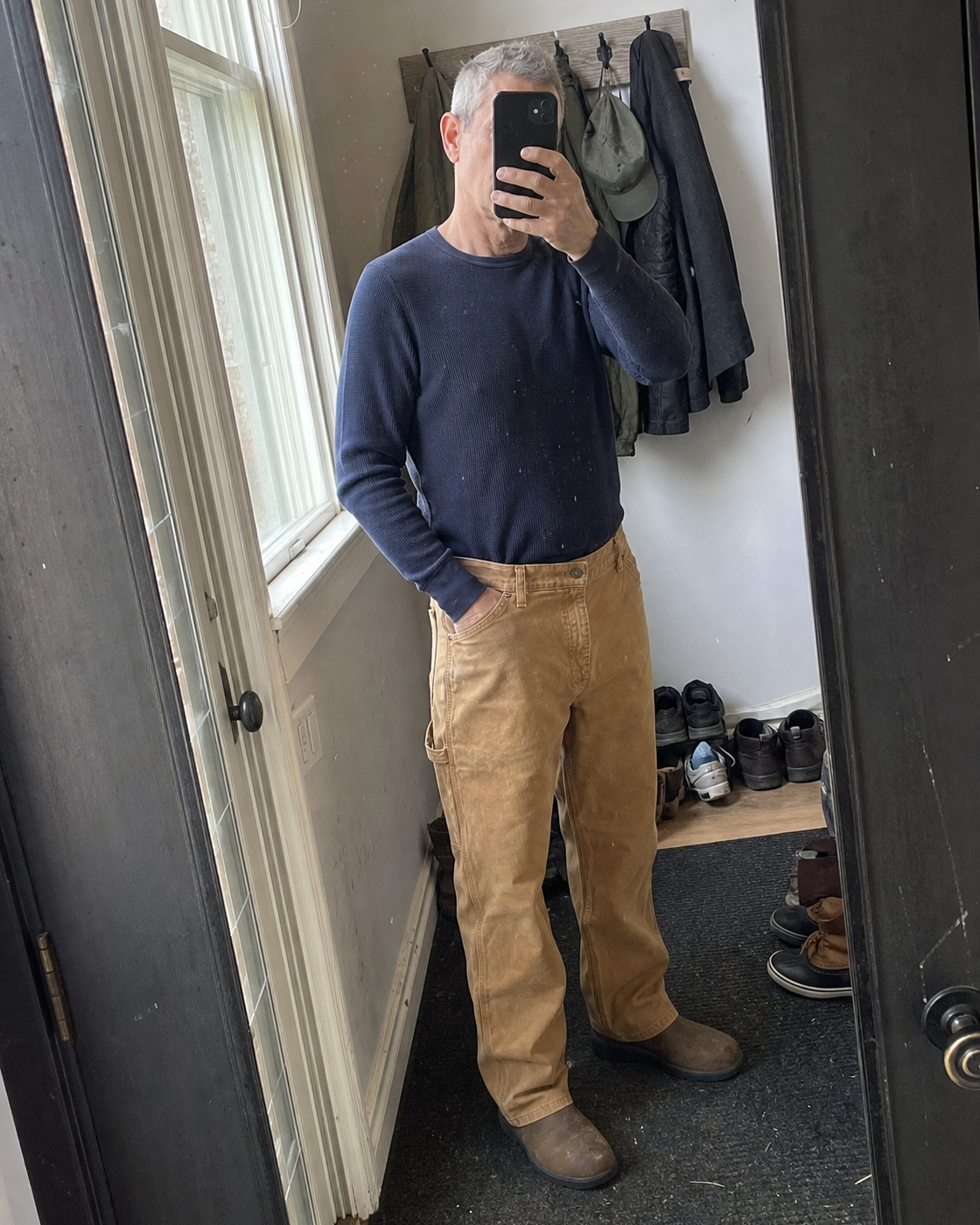 AI style inspiration mirror fit wearing light-tan loose-fit washed duck utility work pants in an entryway