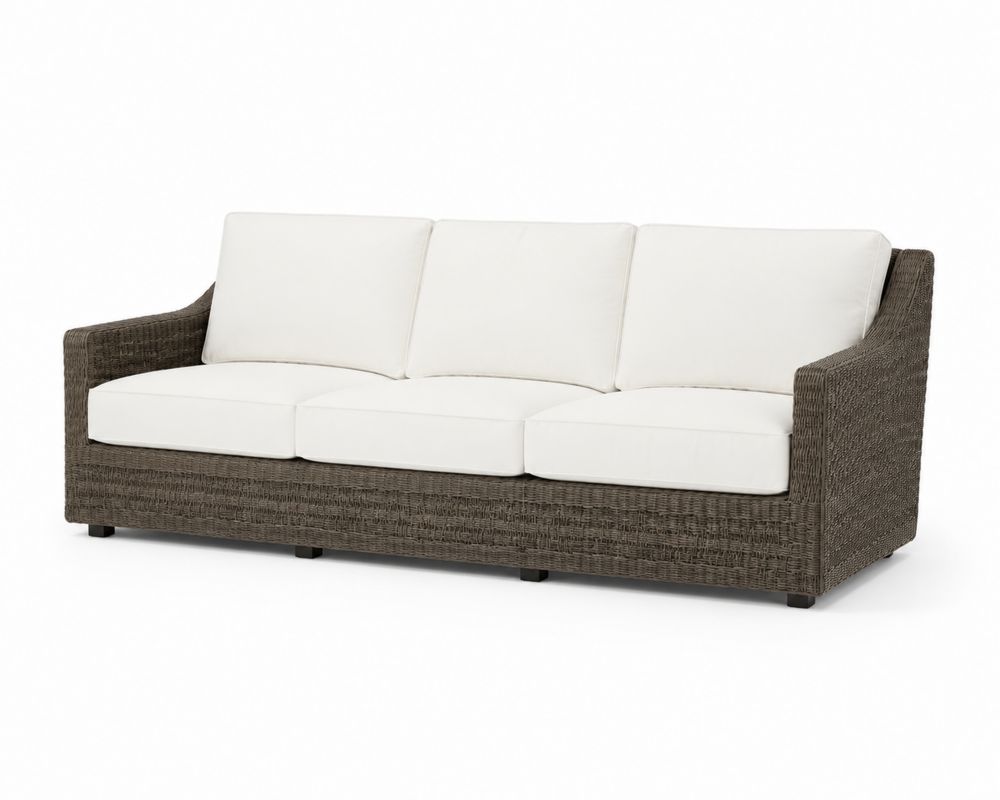 Divano da esterno in rattan intrecciato con cuscini bianchi