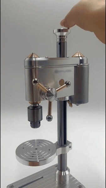 Finger pressing the top knob of a mini drill press