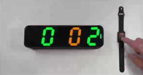 Scoreboard showing 002 while a finger presses the wristband button