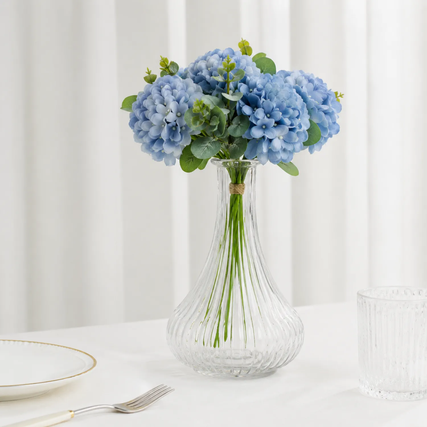 Künstliche blaue Hortensie in einer Glasvase