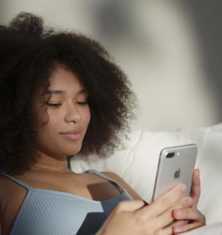 Woman relaxing on a cozy couch, checking her Ovul AI app to confirm ovulation