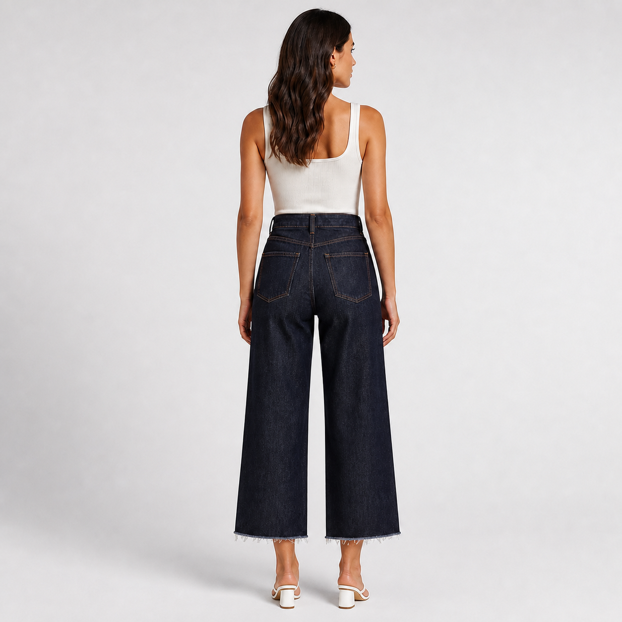 Dark Indigo Denim high rise wide leg cropped jeans back view with matching white strappy heels