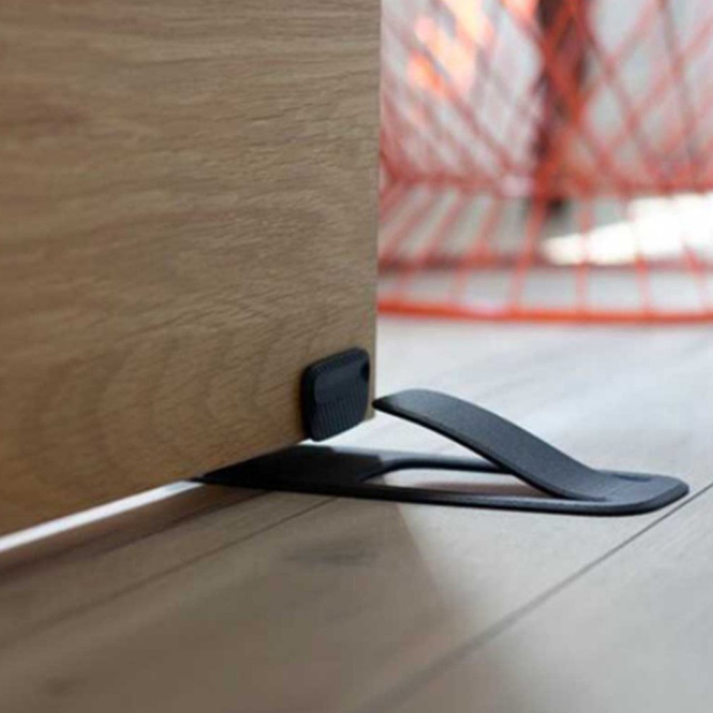 Low profile spring door stopper installed under a wooden door