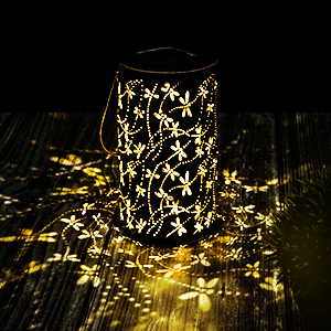 Illuminated decorative jar with star-pattern cutouts creating a glowing effect with warm light casting scattered star shadows.