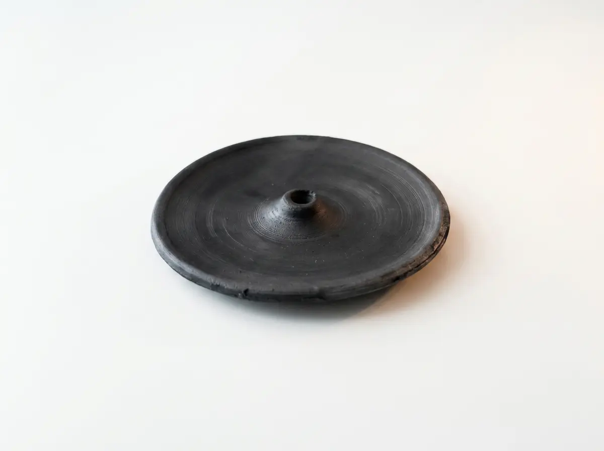 Dawa black pottery incense tray with a circular dish and raised central opening on a light background