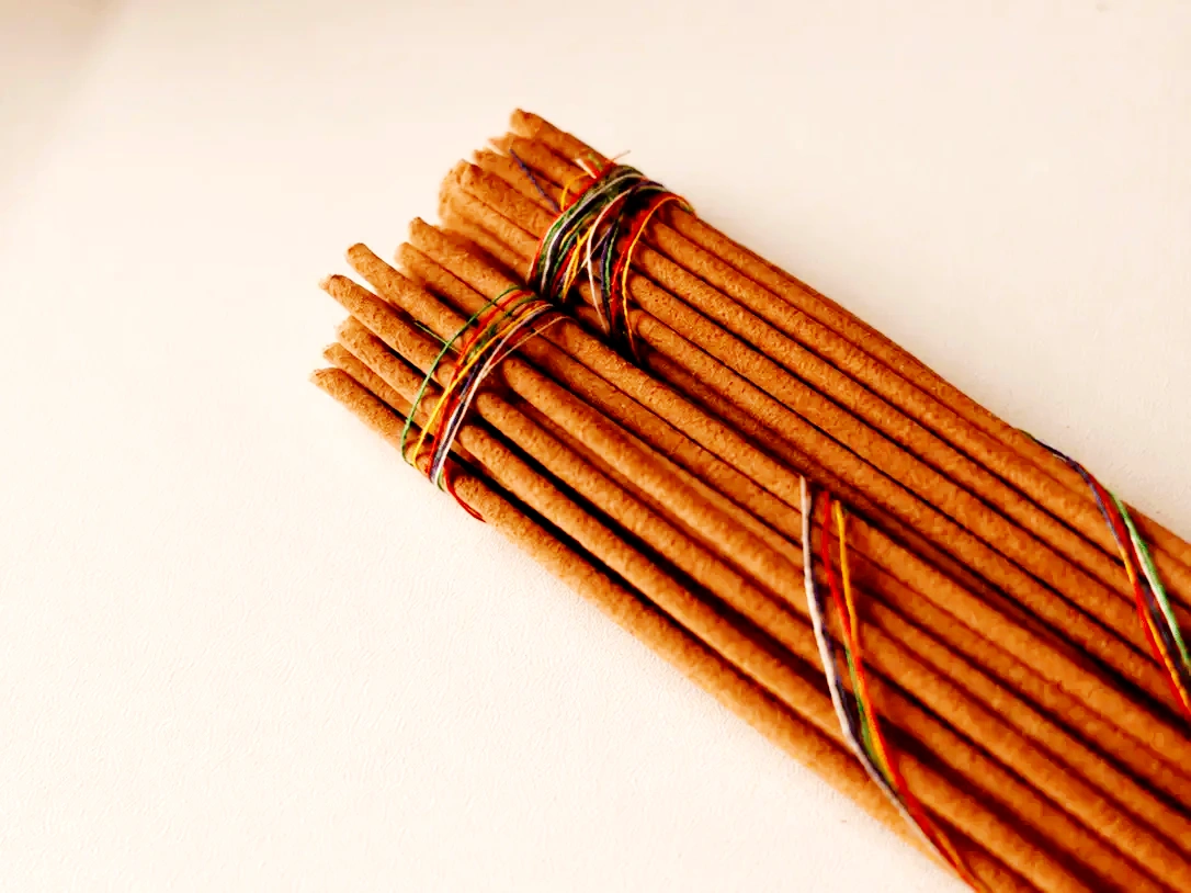 Close-up of a bundle of brown incense sticks tied with thread on a light background