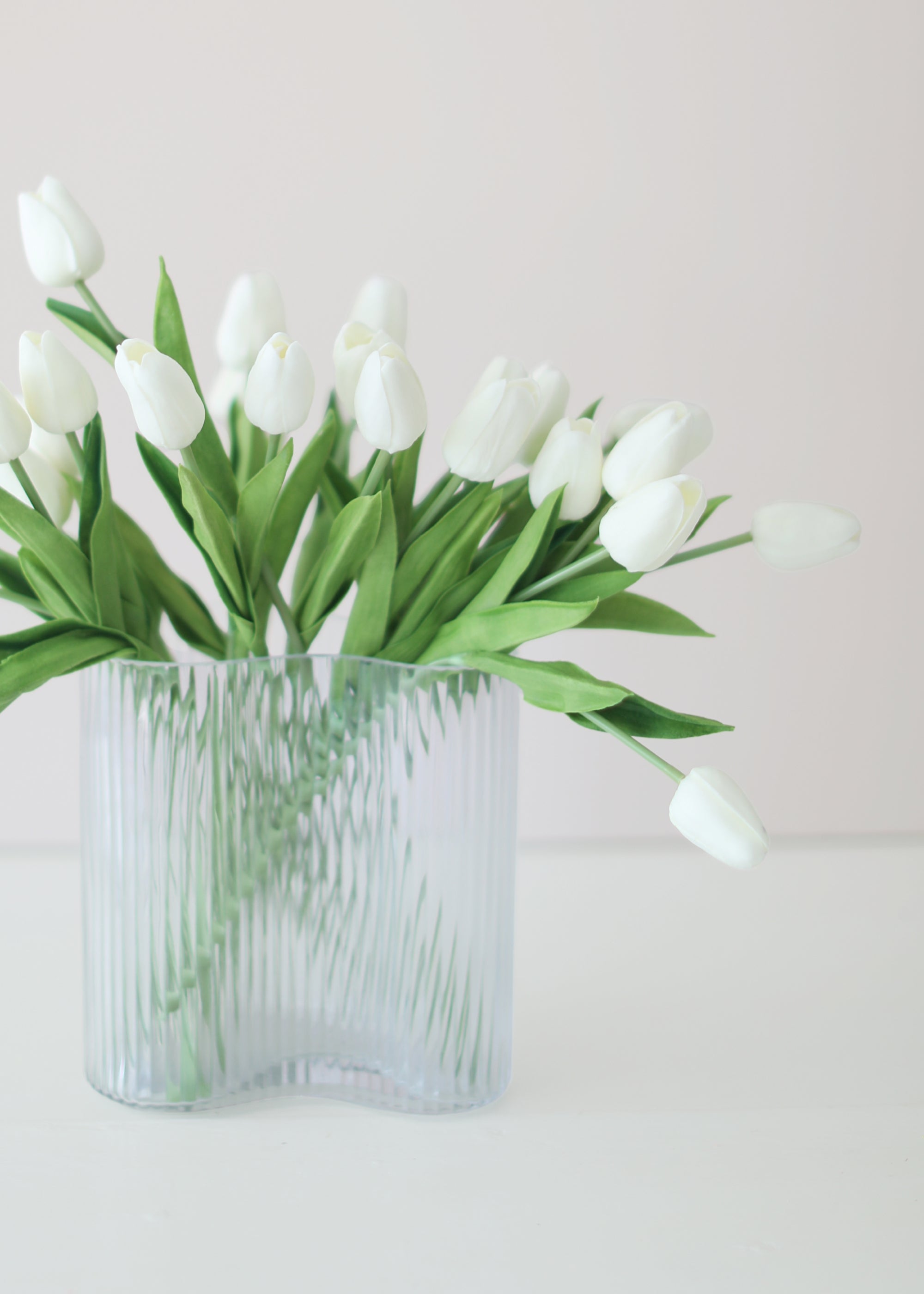 Clear glass vase with white tulips