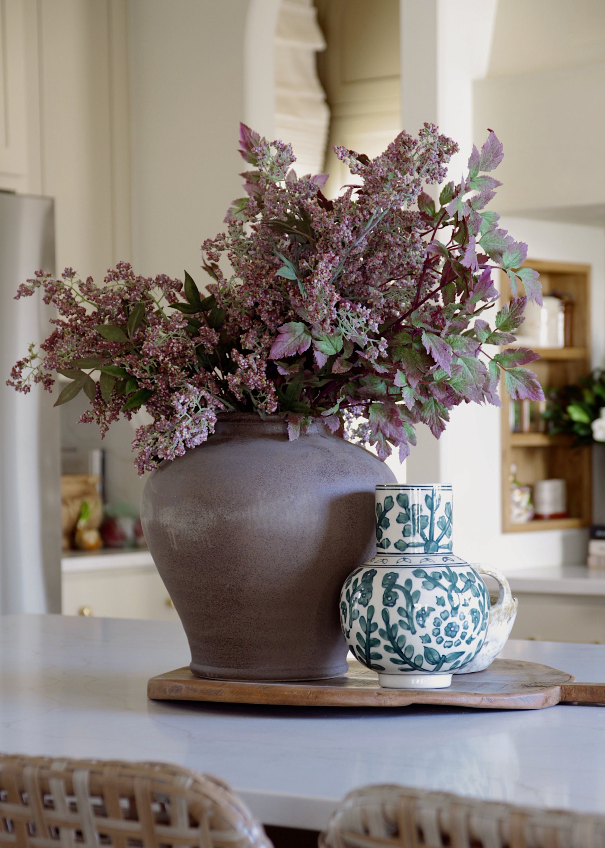 mauve plum berries and cimicifuga arranged in a stoneware vase