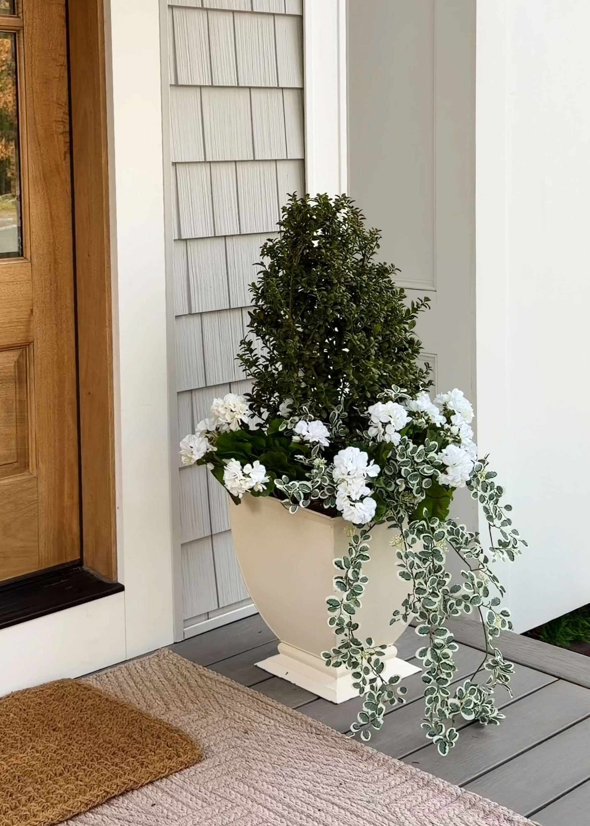 Decorative porch planter with button leaf greenery and white geranium flowers
