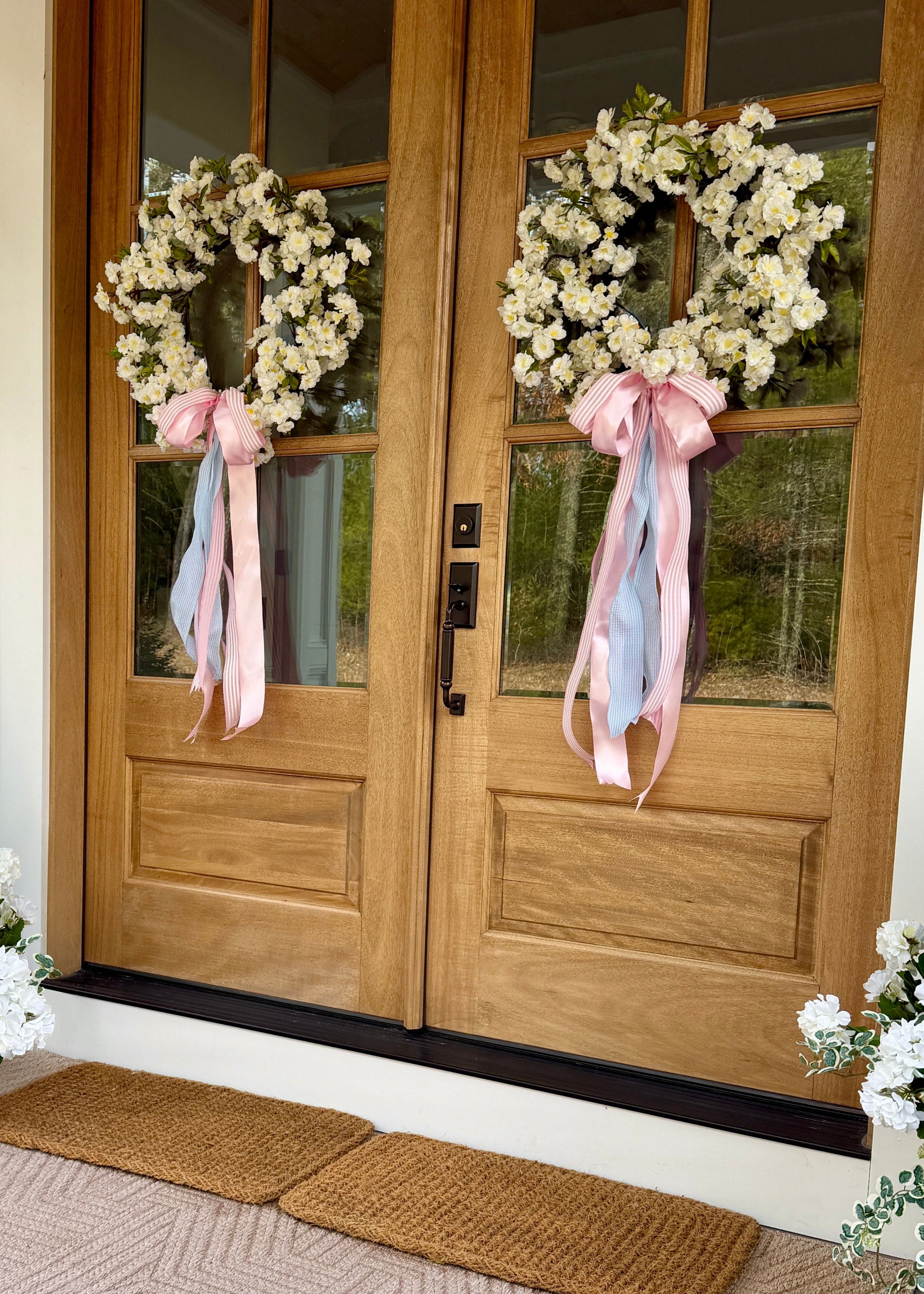 cream white cherry blossom wreaths hung on wooden doors with pink