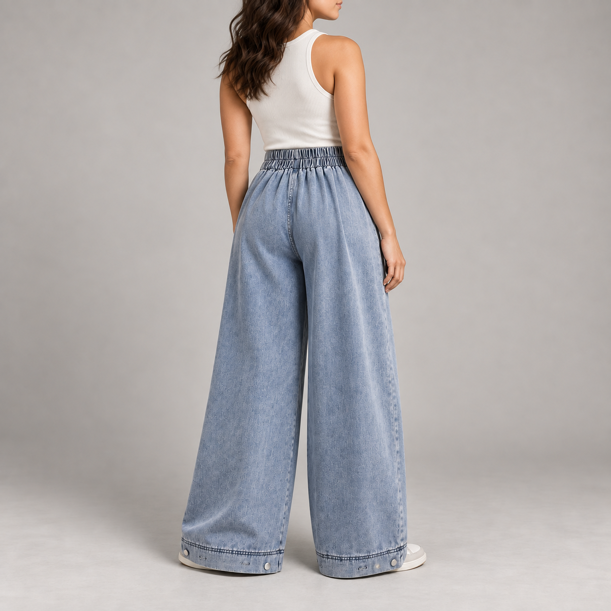 Three-quarter back view of a woman wearing blue balloon jeans with an elastic-back waist and adjustable cuffs