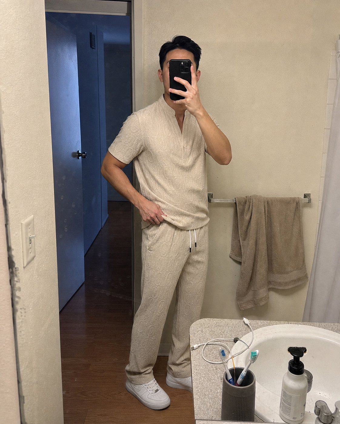 Bathroom mirror three-quarter view of a compact model wearing the Khaki textured V-neck shirt and full-length pants set while checking the side drape
