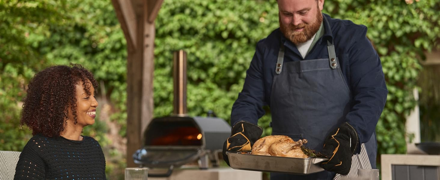 Serving a whole roast chicken cooked in the Ooni Karu 2 Pro oven at an outdoor gathering